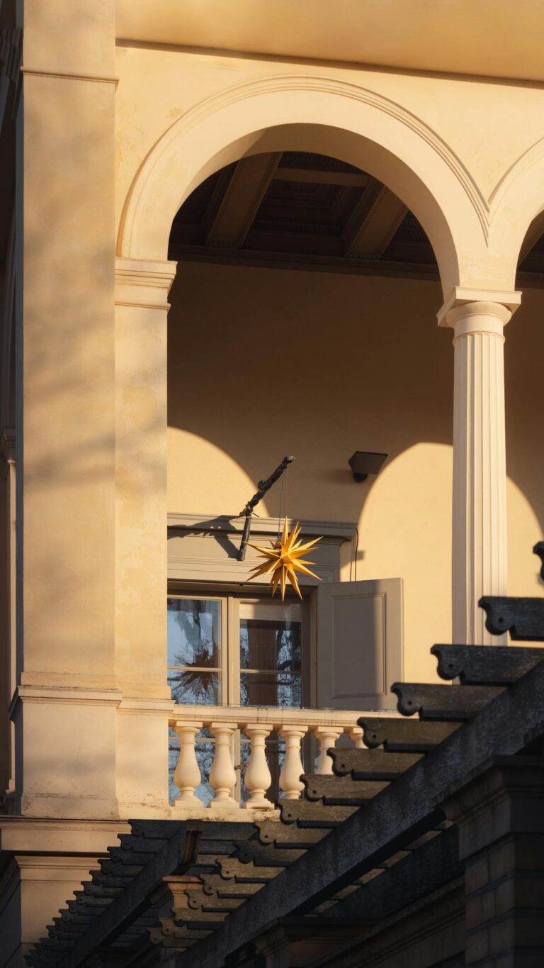 Elegant architectural balcony with golden star ornament, bathed in warm sunlight in Potsdam.